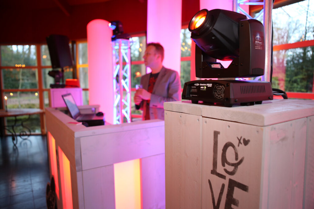 Zijkant van een steigerhouten DJ-booth met LOVE-opdruk en een moving head erop