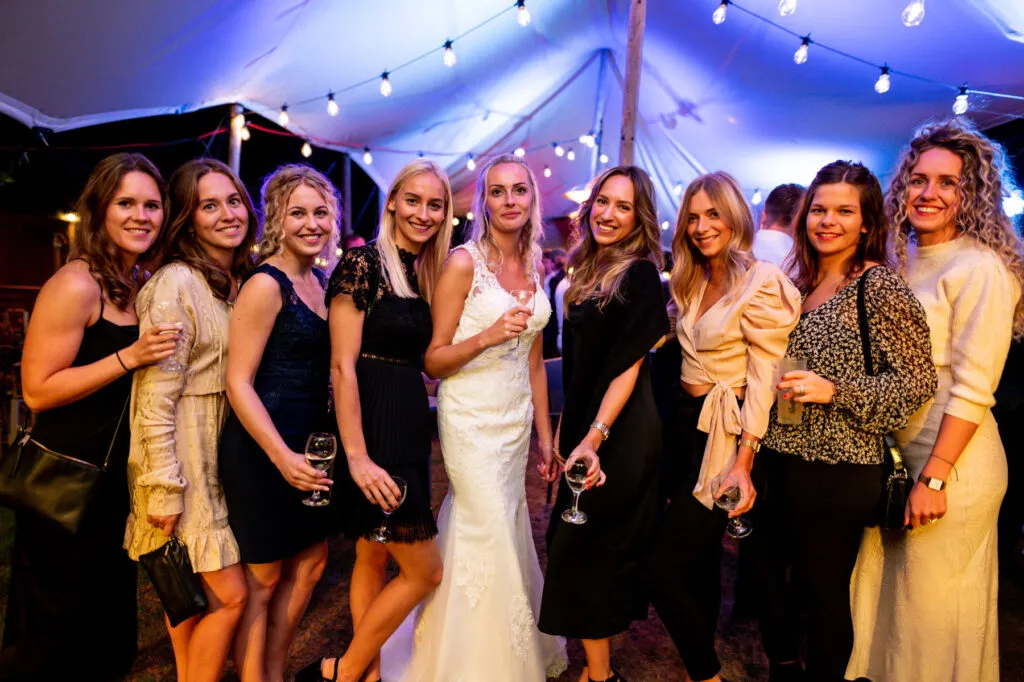 Bruid met haar vriendinnen in een feesttent vol lichtjes