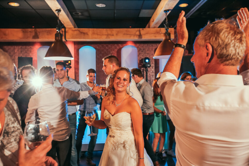 Bruid danst lachend op de volle dansvloer van Pieter Poot tussen de feestende gasten
