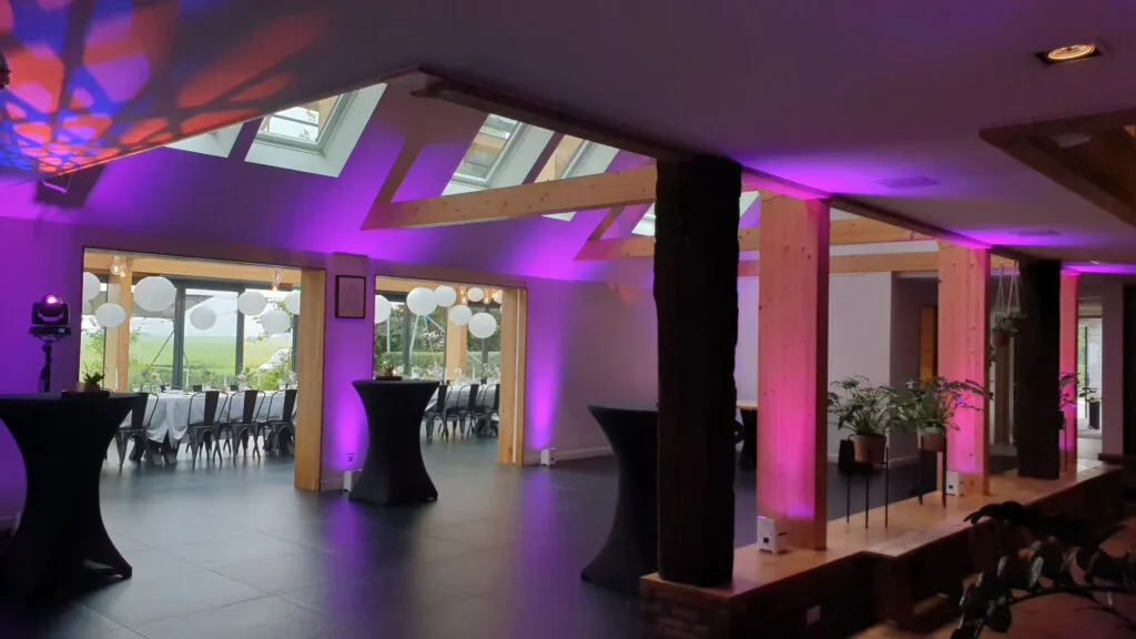 Zaal van de Pollepleats met paarse uplights langs de houten balken