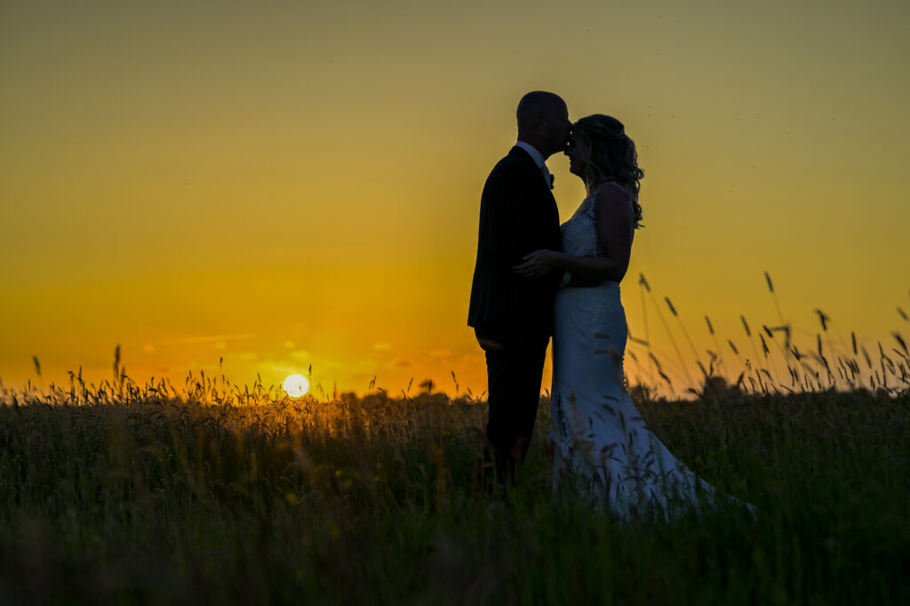 Silhouet van een bruidspaar bij zonsondergang in het Friese landschap bij de Pollepleats