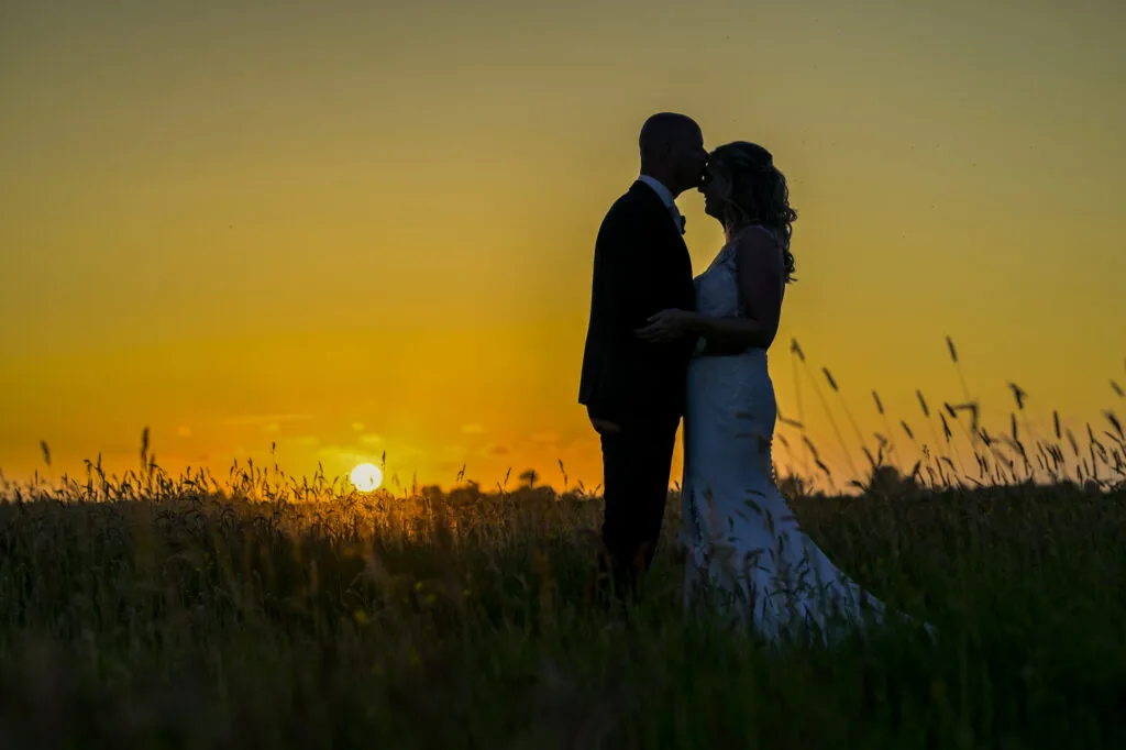 Silhouet van een bruidspaar bij zonsondergang in het Friese landschap bij de Pollepleats