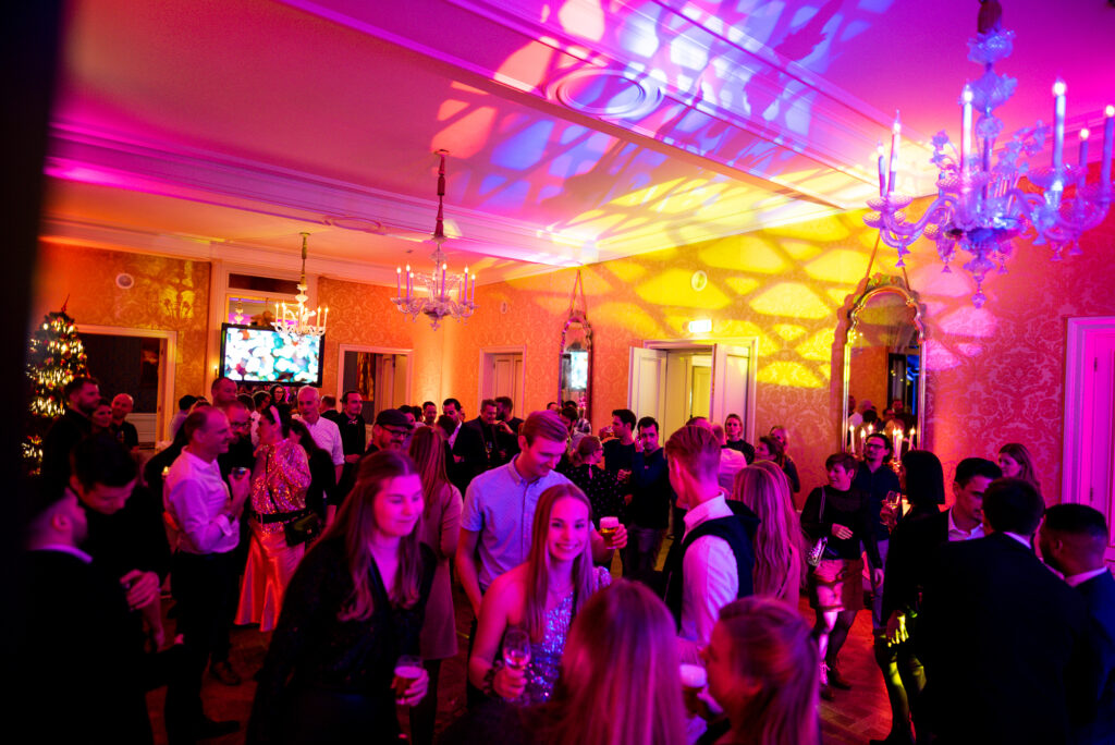 Feestzaal van het Stadhouderlijk Hof met kleurrijke uplights, kroonluchters en dansende gasten