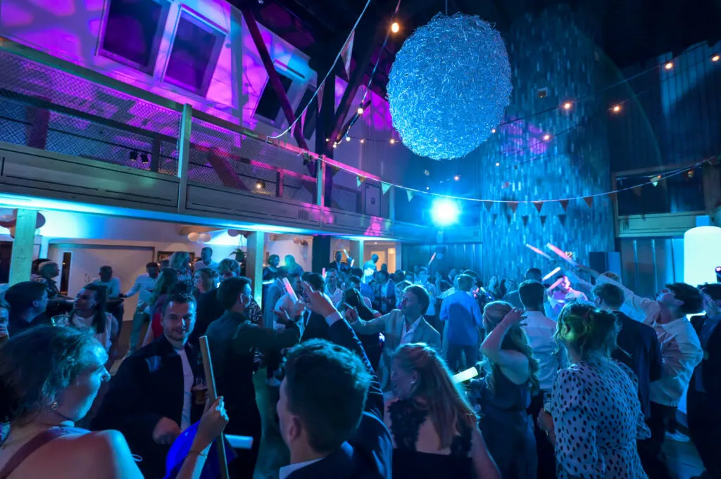 Volle dansvloer met feestende gasten onder een grote lichtbol in De Pollepleats