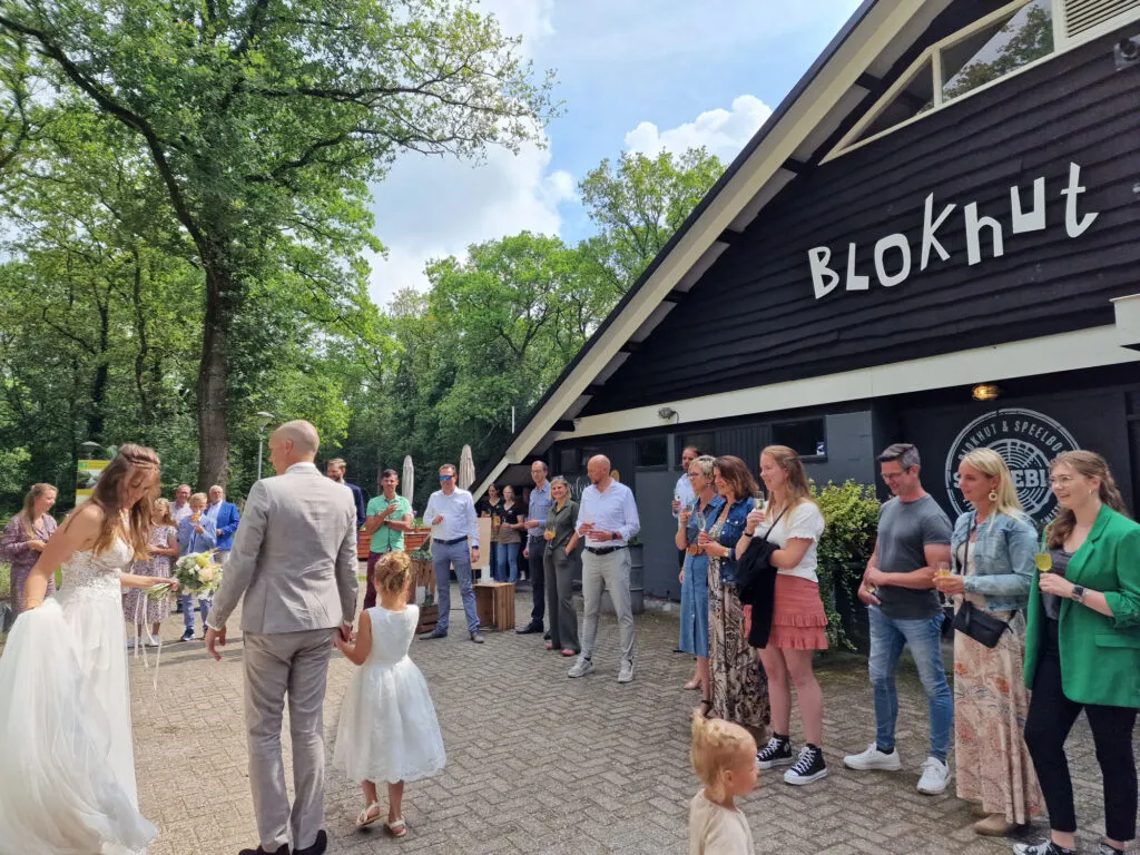 Bruidspaar en gasten voor de blokhut tussen de bomen op Sparjebird bij Beetsterzwaag