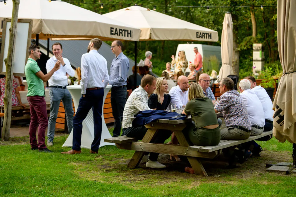 Gasten op het terras tussen de bomen bij de Blokhut op Sparjebird