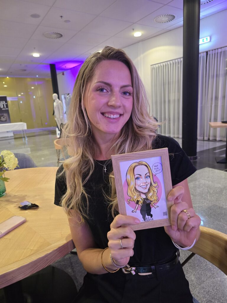 Bezoeker met haar ingelijste karikatuur met de wens Wat leuk dit!